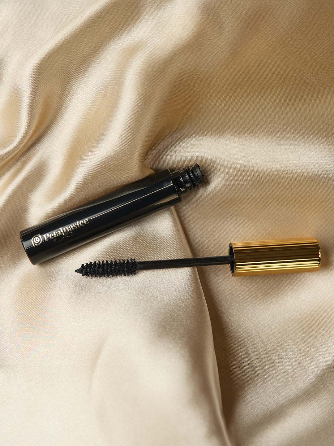 Open Wink It mascara tube and wand on gold fabric